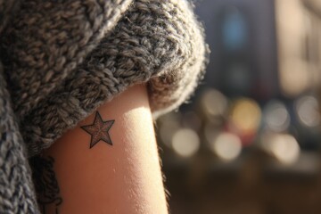 Close-up view of a small star tattoo on a person's arm.