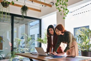 Team of happy business women entrepreneurs working together in office. Two smiling professional...