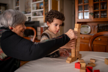 Grandmother and grandchild building tower of wooden blocks