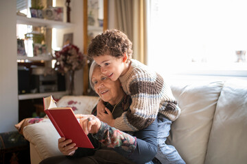 Grandmother and grandchild reading a book together on the sofa