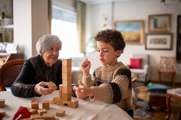Grandmother and grandchild building wooden block tower together