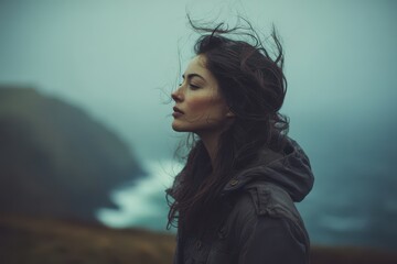 A pensive young woman outdoors on a moody day.