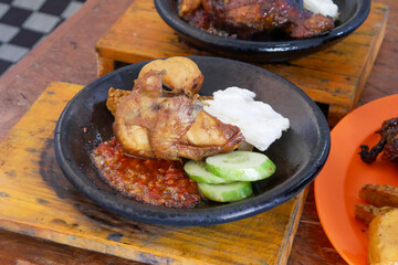 fried chicken in a mortar with chili sauce and fresh cucumber and cabbage