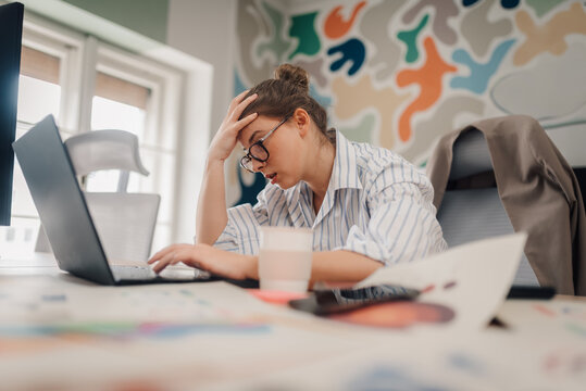 Stressed businesswoman having headache while working on laptop in office