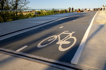 Cycling path with painted bicycle icon indicates dedicated lane for bicycles on modern urban bridge promoting active transportation