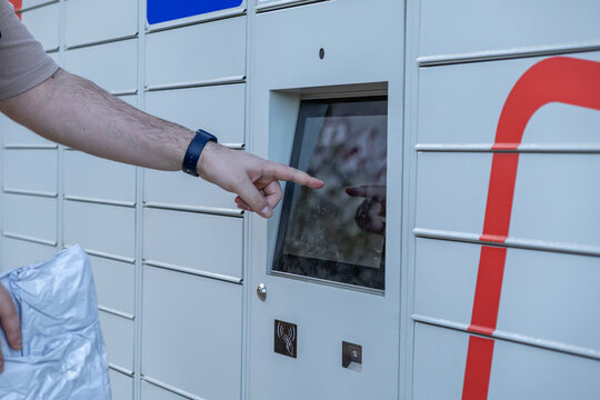 Customer hand touching touchscreen interface on automated parcel locker operating system for modern self-service package access