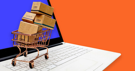Online Shopping. Cardboard boxes of shopping packages in a trolley on top of a laptop keyboard. Concept design of online shopping services on the web