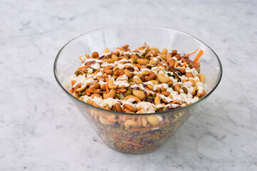 Fresh Broccoli Salad with Cashews in a clear glass bowl with broccoli florets, crunchy cashews, shredded carrots, and red cabbage, drizzled with creamy white sauce side view of healthy salad
