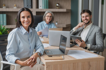 Businesswomen and businessmen looking at the camera during meeting. Happy group of businesspeople...