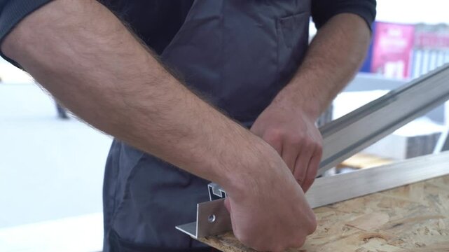 Worker assembles solar panel mount, triangular trusses for mounting solar panels on the roof of a building. Close-up.
