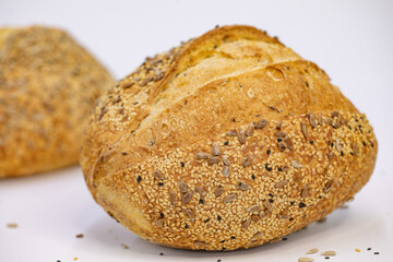 Close-up of a delicious artisan bread loaf with seeds on a white surface