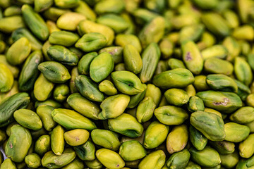 A close-up shot of a pile of fresh, green shelled pistachios.