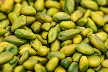 A close-up shot of a pile of fresh, green shelled pistachios.