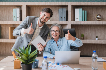 Happy busy executive people working together in office showing thumb up gesture looking at camera....