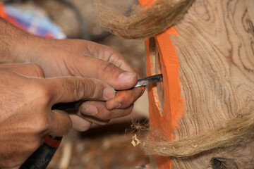 Detail of the hands of a ship's carpenter working on the sternpost of a traditional Mallorcan boat:...