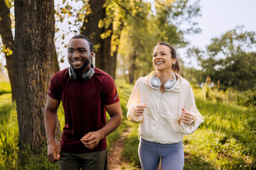 Joyful joggers enjoying a morning run through a green park with headphones on a sunny day