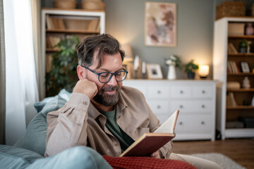 Relaxed man enjoying a book on his living room sofa