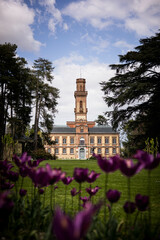 Une maison de maître dans un jardin à la française, le bâtiment est en fond avec au premier plan des fleurs