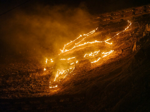 Torches burn on a hillside at night, forming a pattern. Krampus and St Nicholas, 5 December in mining village of Cave del Predil, Tarvisio, Italy.