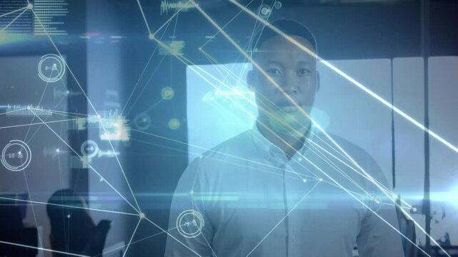 Man standing in tech office, using translucent screen overlaying network data charts
