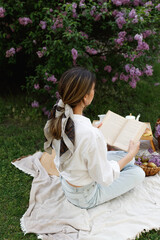 Woman Reads Book During Springtime Picnic Outdoors