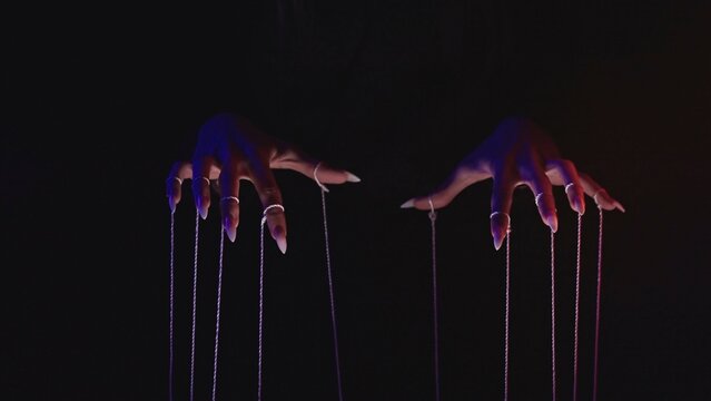 Fototapeta Hands Manipulating Puppet Strings in Dramatic Lighting