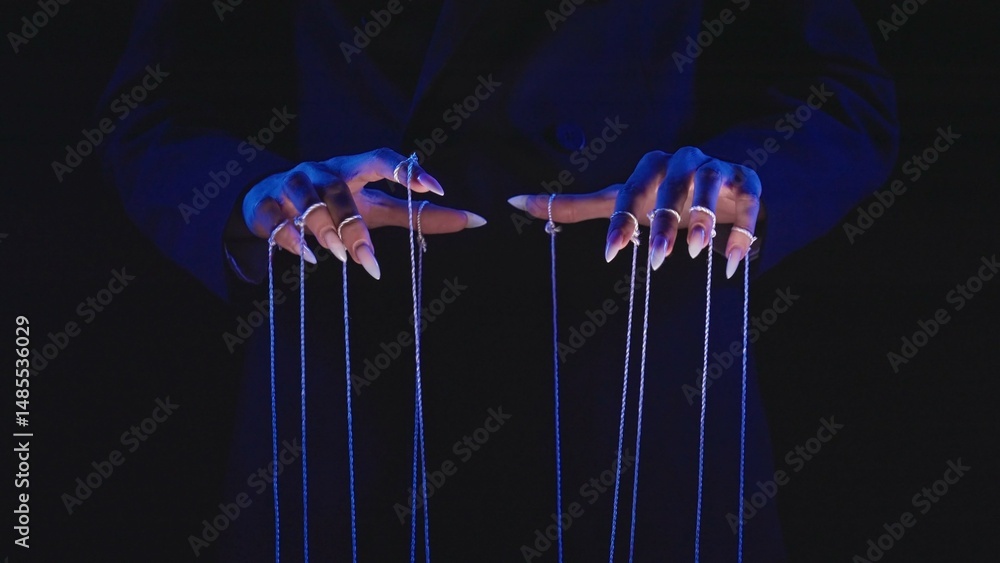 Poster hands with long nails manipulating puppet strings in blue light