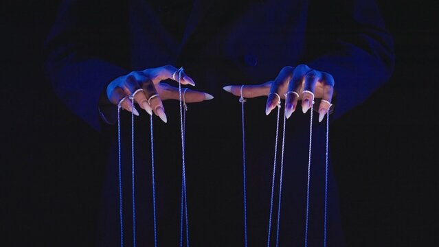Fototapeta Hands with Long Nails Manipulating Puppet Strings in Blue Light