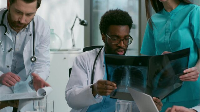 Multiethnic doctors meeting health x-ray conversation group diverse women men African Indian medical students physician medic teamwork discussing checkup laptop pc insurance surgery talking at clinic