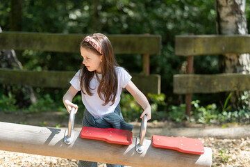 Little long-haired girl with a headband plays on the playground. Children's leisure concept
