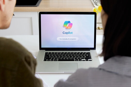 Coworkers using copilot ai companion on laptop in office