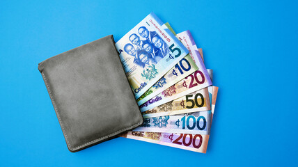 Mens wallet with all Legal tender Ghanaian Cedis money currency notes as of 2025 isolated on blue background
