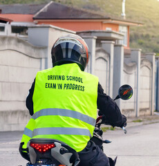 Motorcyclist taking driving school exam riding motorcycle on road