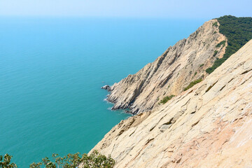 Rugged cliffs reach toward the calm turquoise waters along a scenic coastal landscape