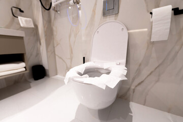 A modern public toilet with paper-covered seat ensuring hygiene and user protection