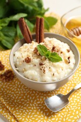 Delicious rice pudding with walnuts, cinnamon, mint and honey on table, closeup