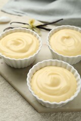 Tasty vanilla pudding with pods and flower on light textured table