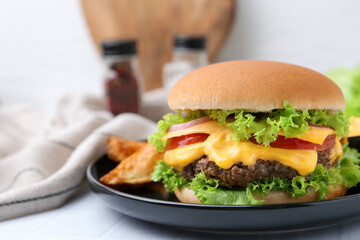Tasty cheeseburger with sauce and potato wedges on white table, closeup