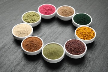 Different superfood powders in bowls on black table