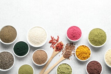 Different superfood powders on light grey table, flat lay. Space for text