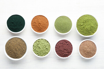 Different superfood powders on white wooden table, flat lay