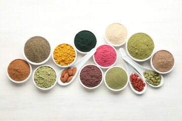 Different superfood powders on white wooden table, flat lay