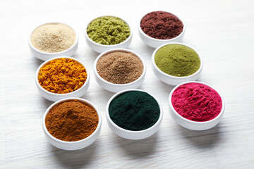 Different superfood powders on white wooden table, closeup
