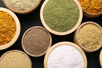 Different superfood powders in bowls on dark table, flat lay