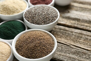 Different superfoods in bowls on wooden table, closeup. Space for text