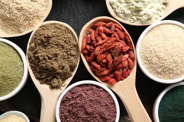 Different superfoods in spoons and bowls on table, flat lay