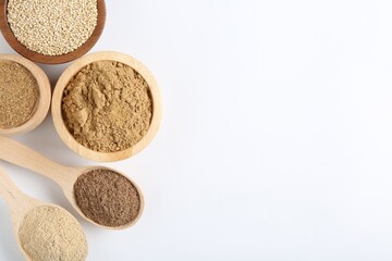 Different superfood powders in bowls and spoons on white background, flat lay. Space for text