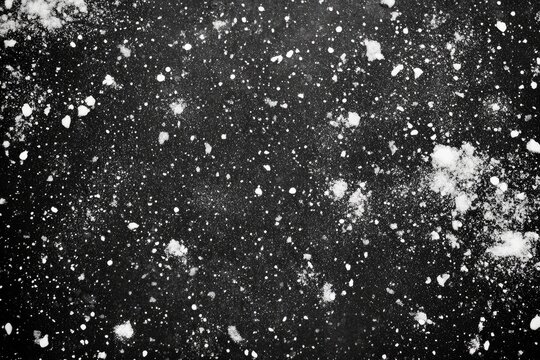 Abstract black and white speckled texture.  Scattered light gray spots on dark background