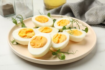 Boiled eggs and microgreens on white marble table, closeup