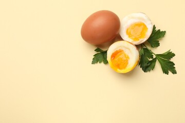 Soft boiled eggs and parsley on beige background, flat lay. Space for text